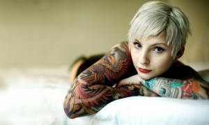 Girl with tattoo on bed background